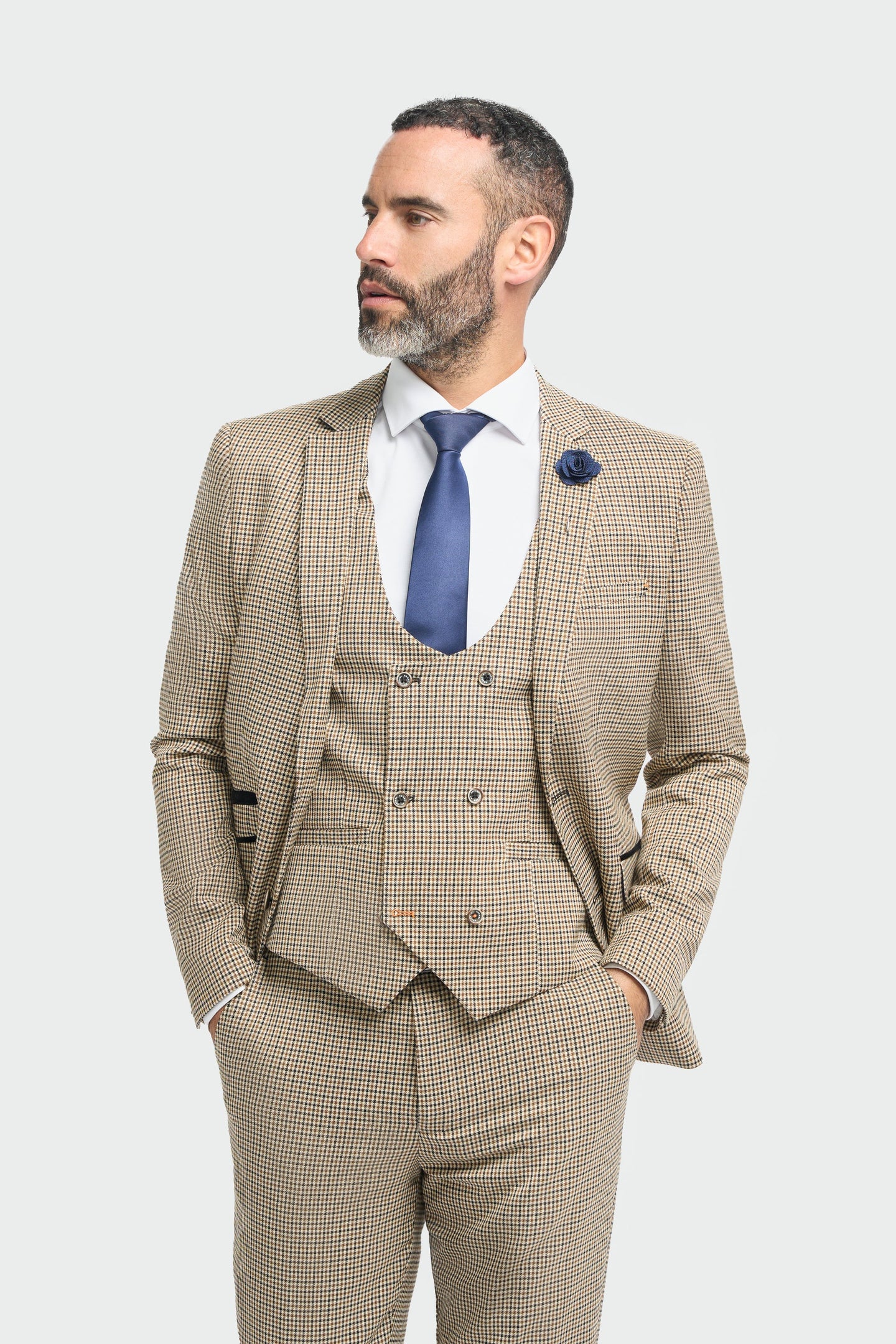 Man wearing a beige checkered suit with a blue tie on a white background